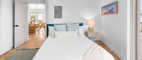 Una camera da letto con un letto, un comodino, una lampada e un quadro appeso al muro.