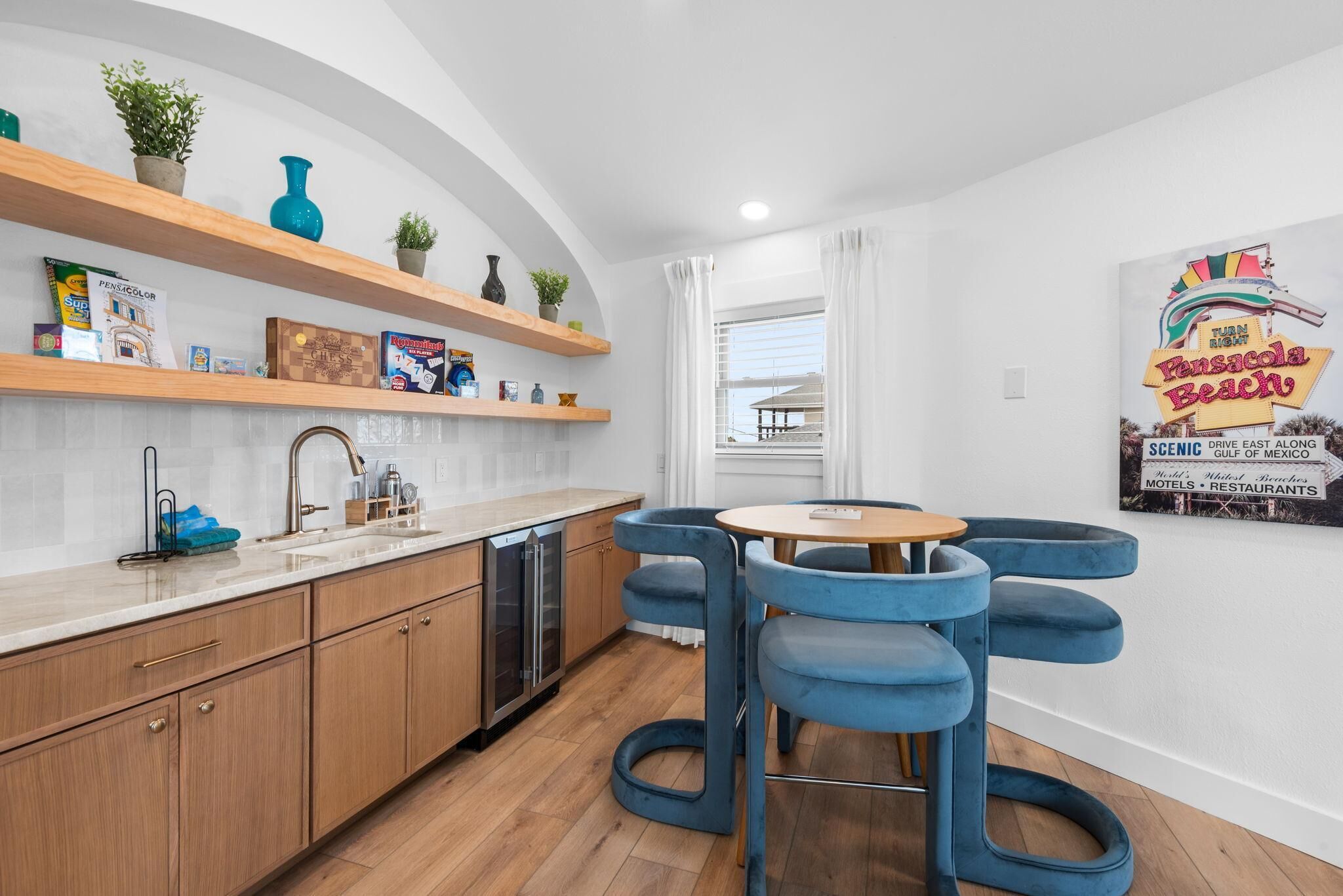 A modern kitchen with wooden cabinets, a dishwasher, and a blue bar stool.