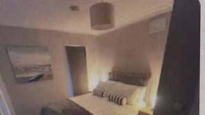 Hotellihuone, jossa on sänky, työpöytä ja tuoli.