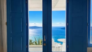 Una habitació amb un gran finestral que dona a una piscina i a una vista panoràmica del mar i les muntanyes.