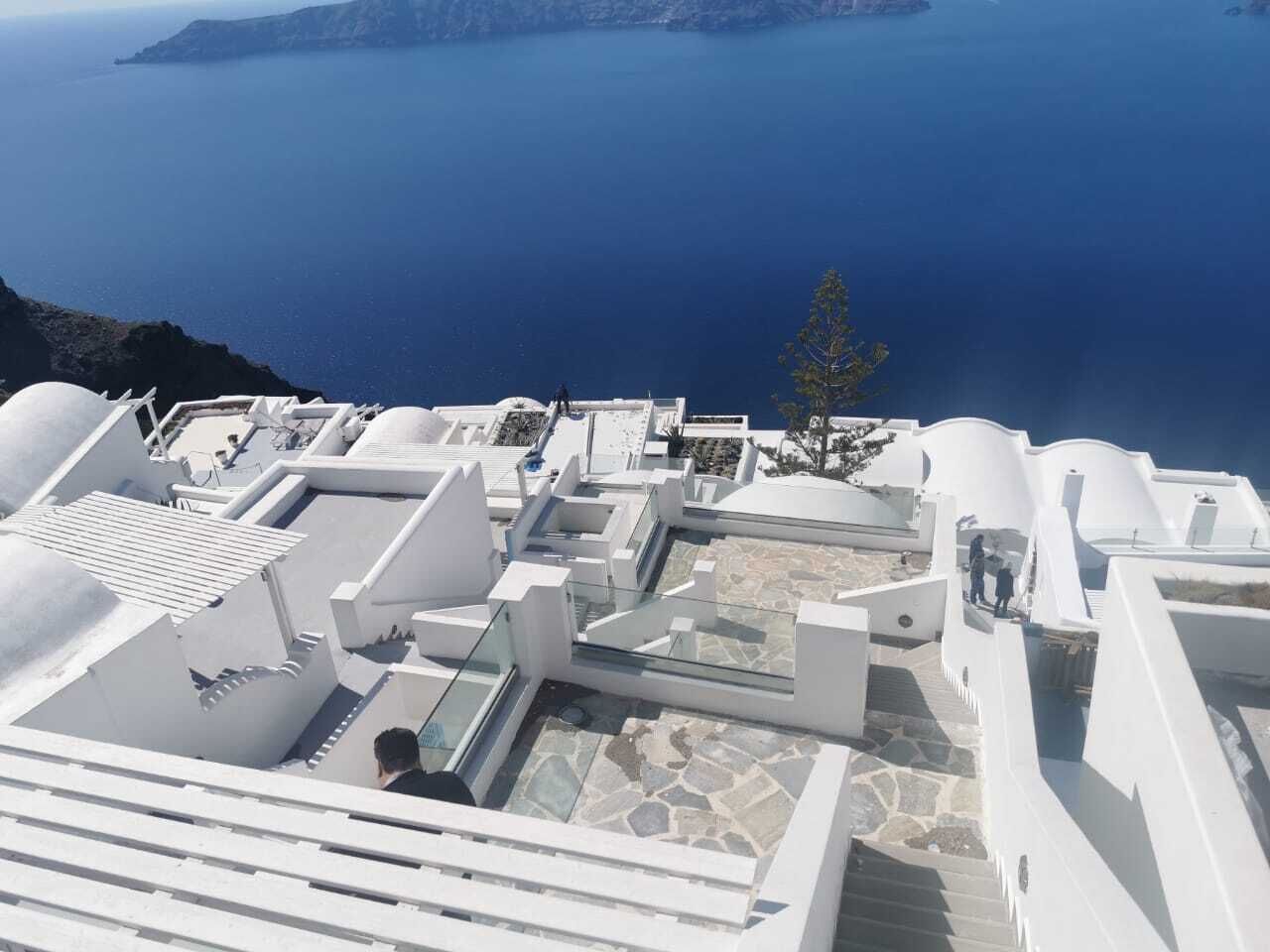 A white building with a rooftop terrace overlooking a body of water.