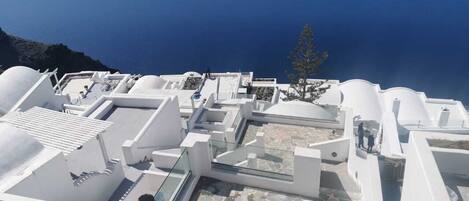 A white building with a rooftop terrace overlooking a body of water.