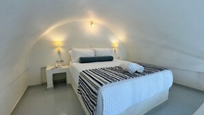 Ein Einzelbett mit gestreifter Bettdecke, zwei Nachttischlampen, ein kleiner Nachttisch und eine Wandleuchte.