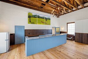 A kitchen with a wooden ceiling, a blue counter, and a refrigerator.