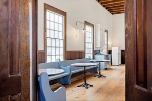 A room with wooden floors, a bench seating area, a table, and a refrigerator. - Historic Church Turned Home in Charlottesville (Scottsville)