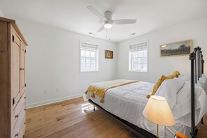 A bedroom with a bed, a ceiling fan, two windows with curtains, a bedside lamp, and a wooden wardrobe. - Historic Church Turned Home in Charlottesville (Scottsville)