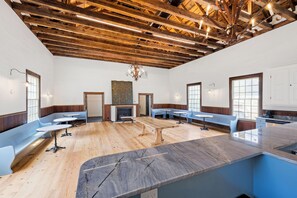 A spacious room with wooden beams, a fireplace, and seating areas.