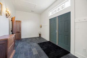 A hallway with a wooden door, a black rug, and a wall-mounted light fixture. - Historic Church Turned Home in Charlottesville (Scottsville)