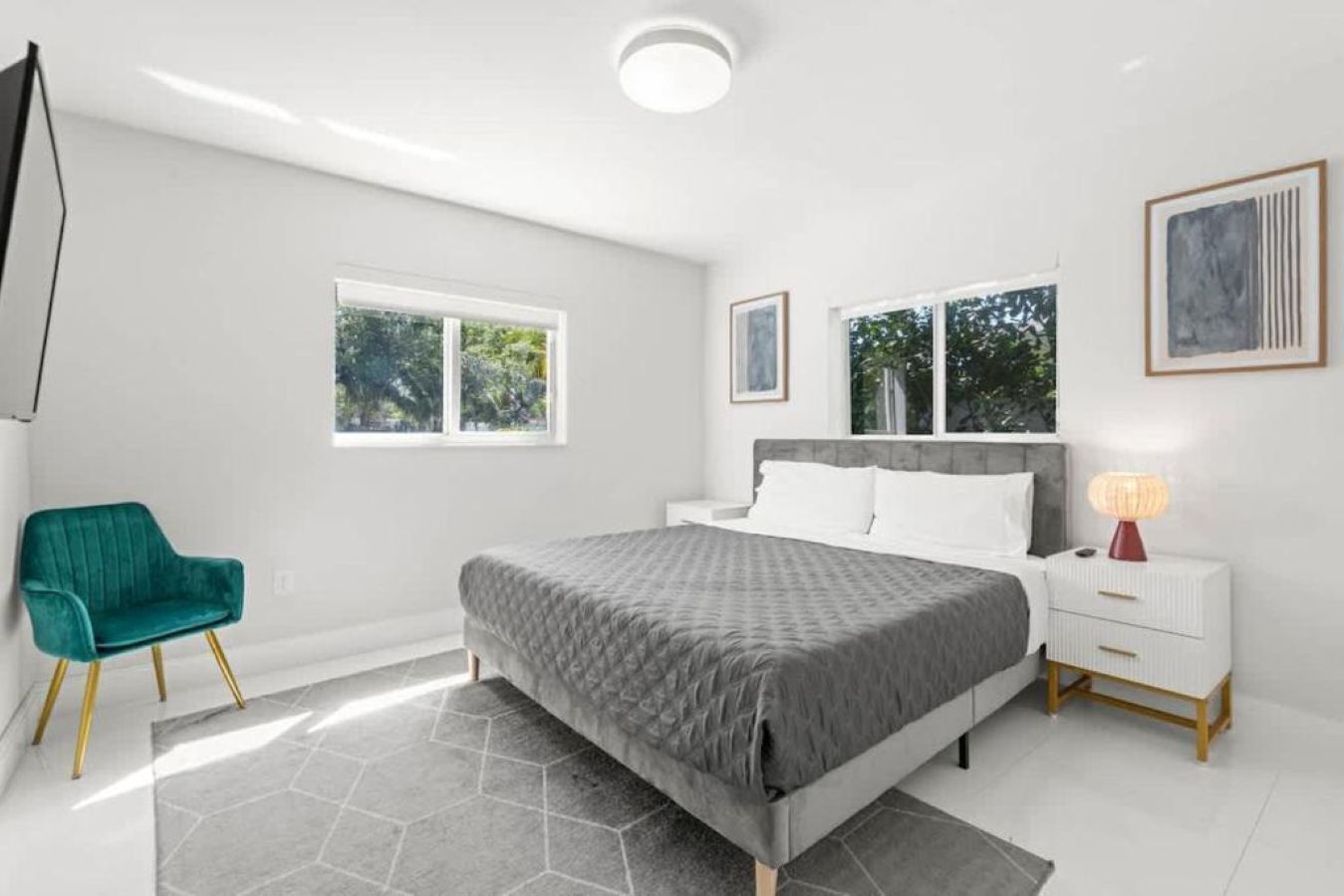 A bedroom with a bed, a nightstand, a chair, and a window.