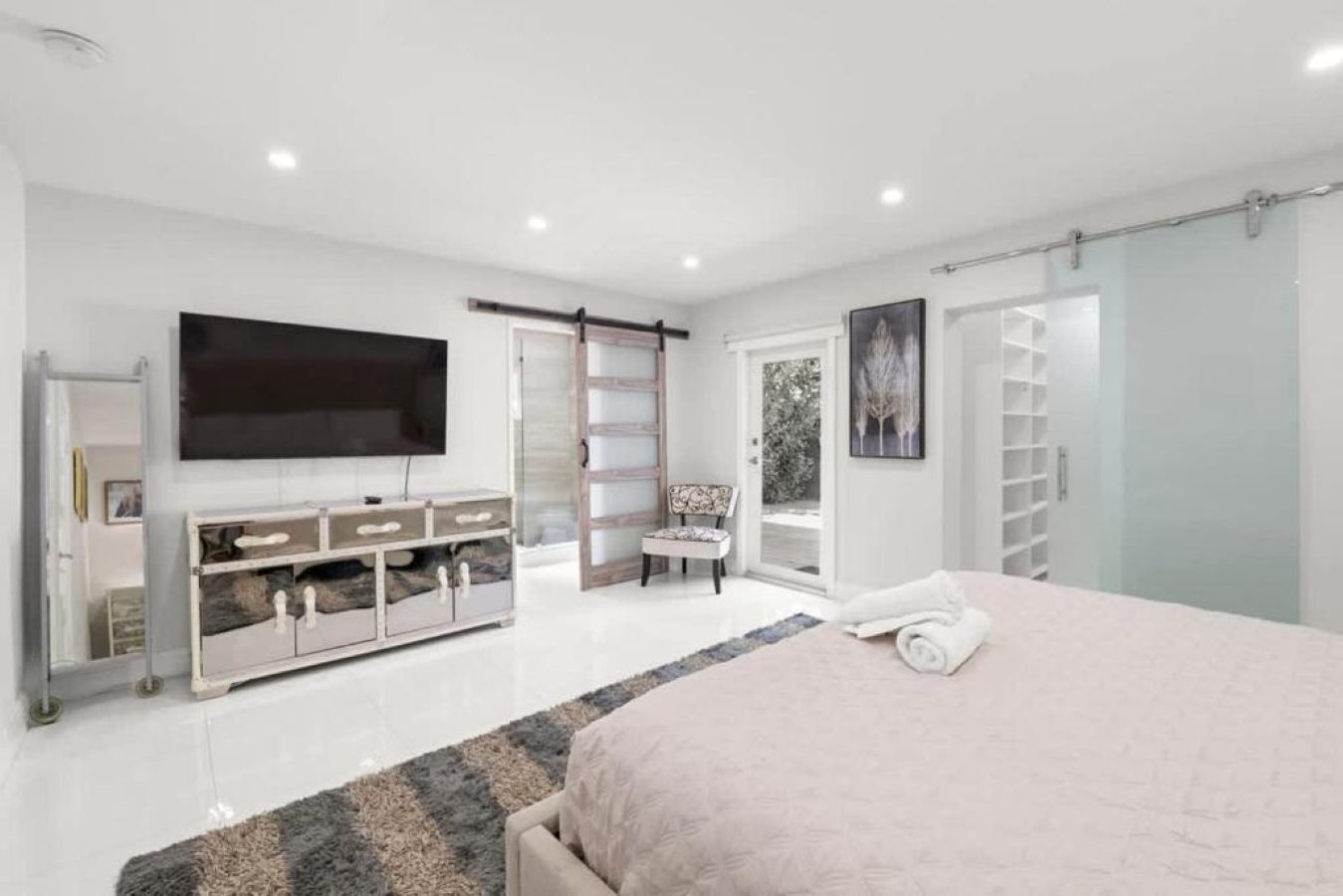 A bedroom with a bed, a TV, a wardrobe, a chair, and a sliding door.