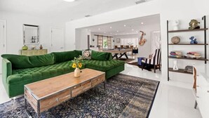 A modern living room with a green sofa, a wooden coffee table, and a patterned rug. - Casa Oasis by Glam Homes (Ojus)