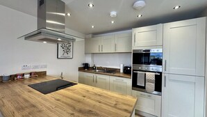 Una cocina moderna con encimera de madera, electrodomésticos de acero inoxidable y muebles de color claro.