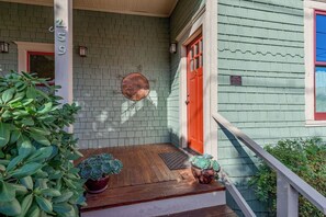 A porch with a wooden floor, a red door, and a mailbox. - Casa Soleil: Luxurious Cottage Steps Away from Downtown Ashland (Ashland)