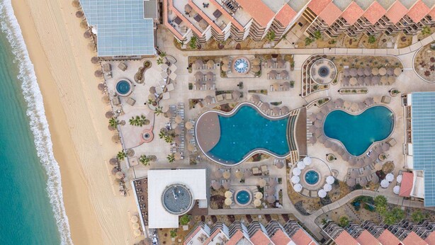 An aerial view of a resort with multiple swimming pools, sun loungers, and a beach. - Spend Thanksgiving in a 3-bedroom hotel suites with AC in Cabo San Lucas (Cabo San Lucas)