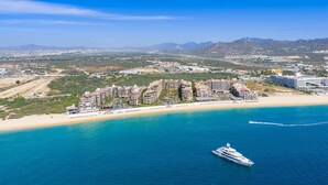 A coastal resort with multiple buildings, a beach, and a yacht in the water. - Spend Thanksgiving in a 3-bedroom hotel suites with AC in Cabo San Lucas (Cabo San Lucas)