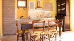 A kitchen with wooden cabinets, a dining table with chairs, and a window with a curtain.