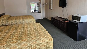 Una habitación de hotel con una cama grande, un aparador, un televisor y un microondas.