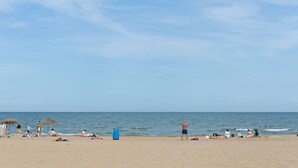 Una playa con gente relajándose, sombrillas y sillas de playa.