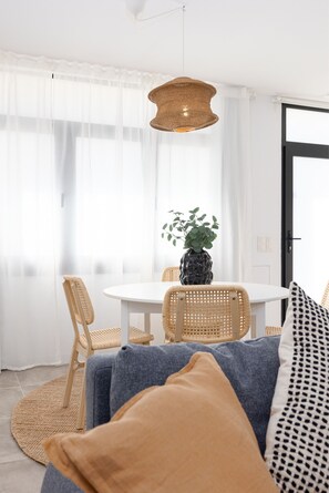 A dining area with a round table, wicker chairs, a hanging light fixture, and a potted plant. - Cabanyal Station A. WiFi + 3 Pax (Valencia / València)