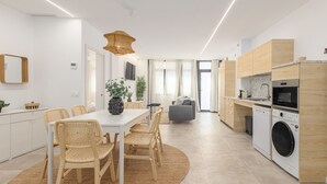 Eine moderne Küche mit Essbereich, Holzschränken, einer Waschmaschine und einem großen Fenster.