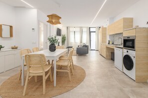 Une cuisine moderne avec un coin repas, des meubles en bois, un lave-linge et une grande fenêtre.