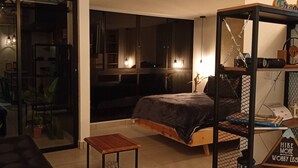 A modern bedroom with a bed, a small table, a bookshelf, and a large window. - Naki Apartamento Santa Rosa de Cabal (Santa Rosa de Cabal)
