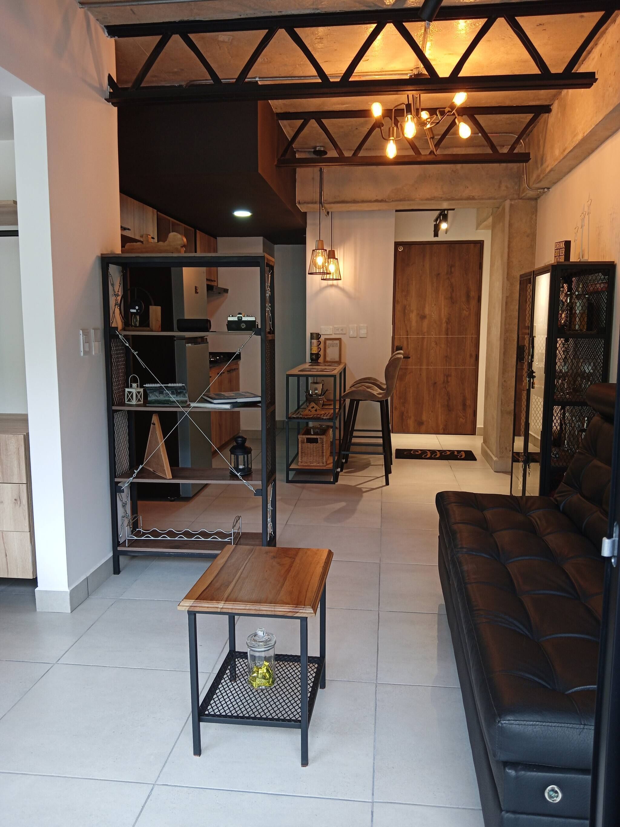 Una sala de estar con un sofá, una mesa de centro, una estantería y un comedor con una silla.