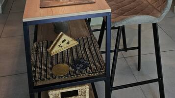 Zona pranzo con tavolo in legno, due sedie, lampadario a sospensione e una porta sullo sfondo.