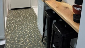 Eine kleine Küche mit einem Kühlschrank, einer Spüle und einer Holzausziehtafel.