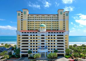 Un hôtel à plusieurs étages doté d’un dôme central, d’un grand parking souterrain et offrant une vue sur la plage.