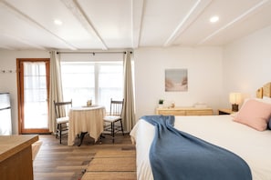 A room with a bed, a table with chairs, a window, and a door. - Edelweiss Inn Nova Scotia (Middleton)