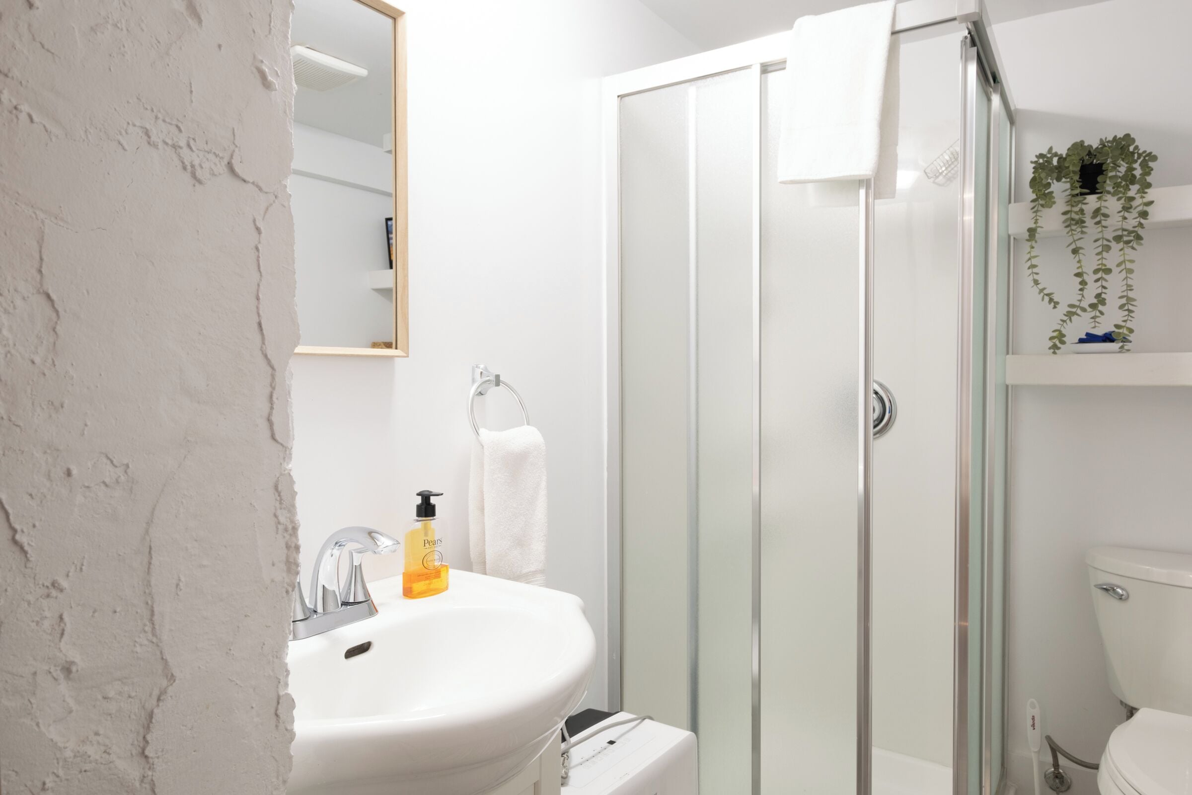 A bathroom with a white sink, a glass shower enclosure, and a white toilet.