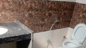 A bathroom with a marble sink, a toilet, and a shower. - HOTEL SHIVALIKA (Jaipur)