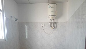 A bathroom with a toilet, a shower, and a water heater. - HOTEL SHIVALIKA (Jaipur)
