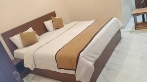 A neatly made bed with a wooden headboard, white bedding, and a brown throw blanket. - HOTEL SHIVALIKA (Jaipur)