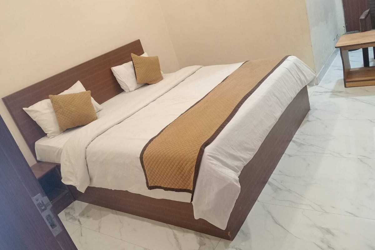Una cama bien hecha con cabecera de madera, ropa de cama blanca y una manta marrón.