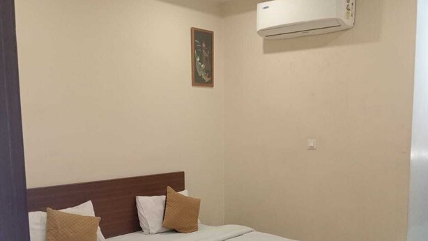 A bedroom with a bed, a ceiling fan, an air conditioning unit, and a wall-mounted picture. - HOTEL SHIVALIKA (Jaipur)