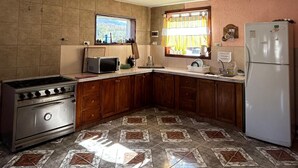 Une cuisine équipée d’une cuisinière, d’un réfrigérateur et d’une fenêtre avec des rideaux.