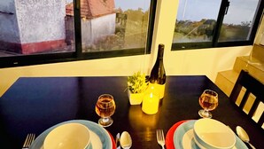Een eettafel gedekt voor twee personen, met borden, bestek, glazen, een kaars en een fles.