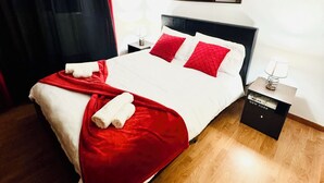 Een hotelkamer met een bed, nachtkastje, lamp en een geometrisch lampenarmatuur.