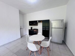 A modern kitchen with a white refrigerator, black cabinets, and a round dining table with white chairs. - At the edge of the city, 5 minutes from PGE and Torre Chiapas! Loft Mango (Tuxtla Gutiérrez)
