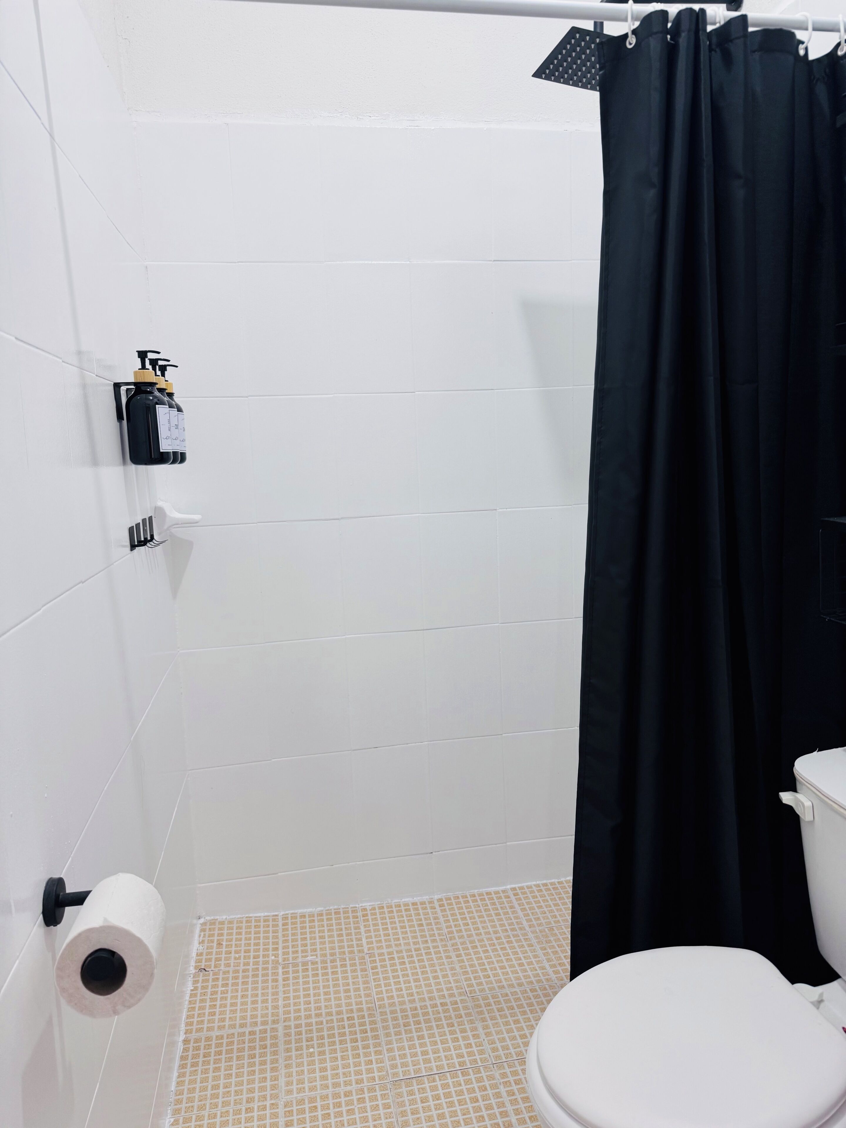 Ein Badezimmer mit Toilette, Duschvorhang, Handtuchhalter und Toilettenpapierhalter.