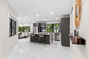Una cocina moderna con una isla central, taburetes de bar y vistas al exterior.