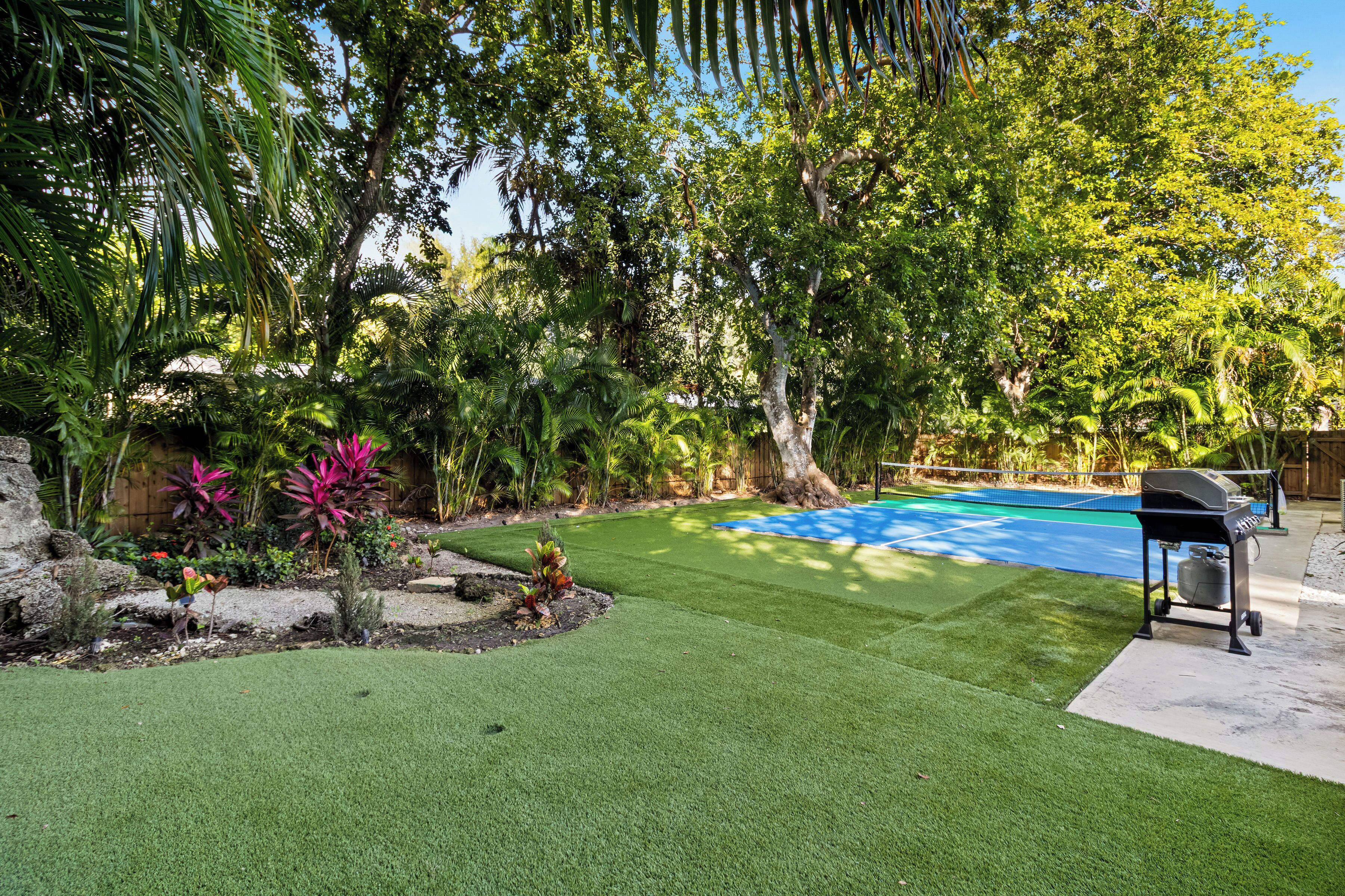 A backyard with a swimming pool, artificial grass, and a barbecue grill.