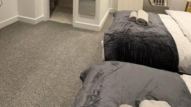 A hotel room with two beds, a bathroom, and a staircase leading to an upper floor.