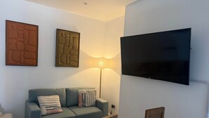 A living room with a sofa, a television mounted on the wall, and a lamp.