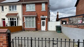 A residential area with a paved driveway, a gated entrance, and a brick wall.
