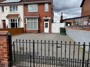 Un quartier résidentiel doté d’une allée pavée, d’une entrée fermée par un portail et d’un mur en briques.