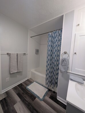 A bathroom with a bathtub, a shower curtain, a towel rack, and a sink. - Modern Cozy Home, Free Parking, Near Downtown (Dayton)