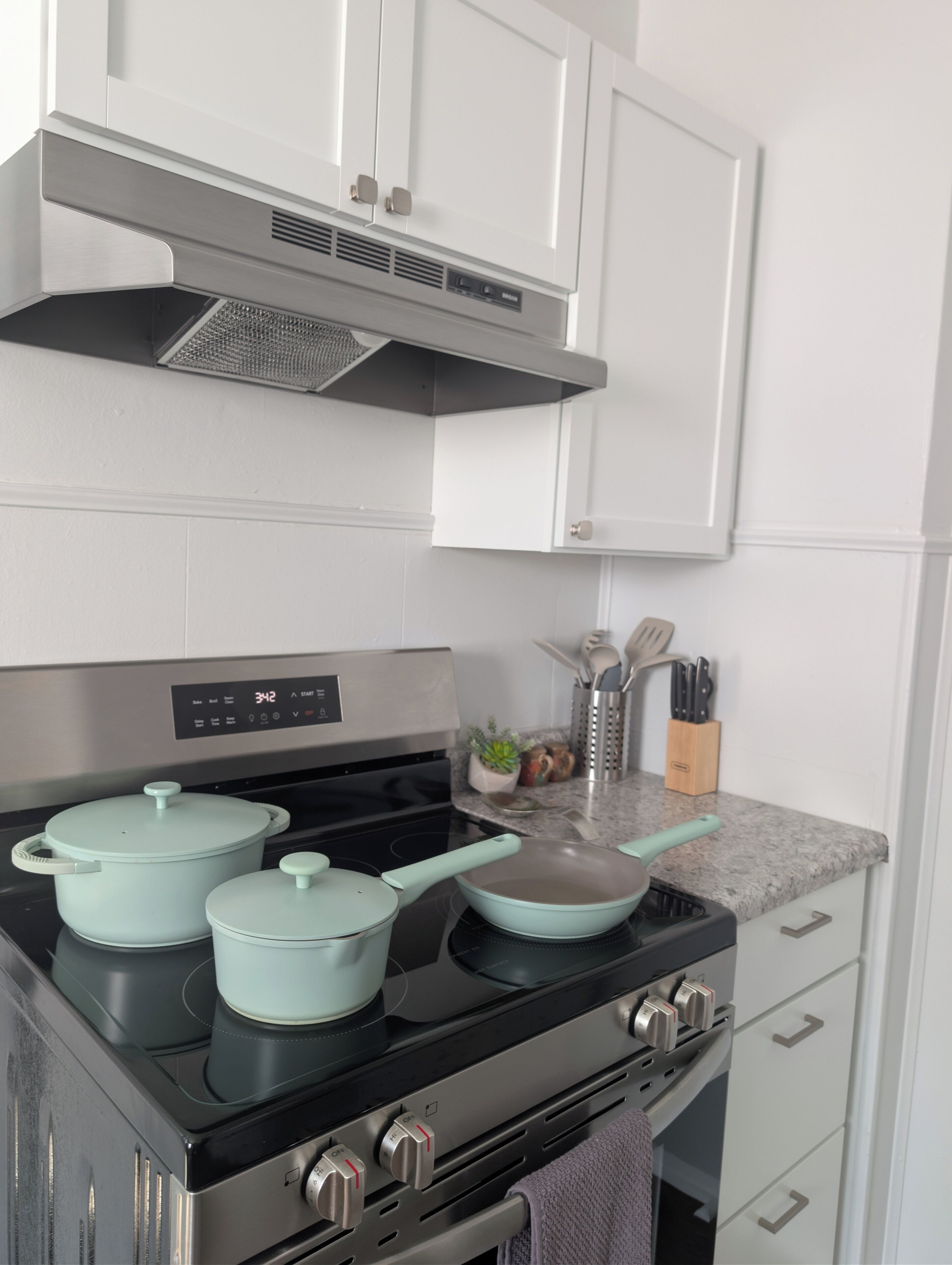 A kitchen with a stove, pots, and a digital clock.